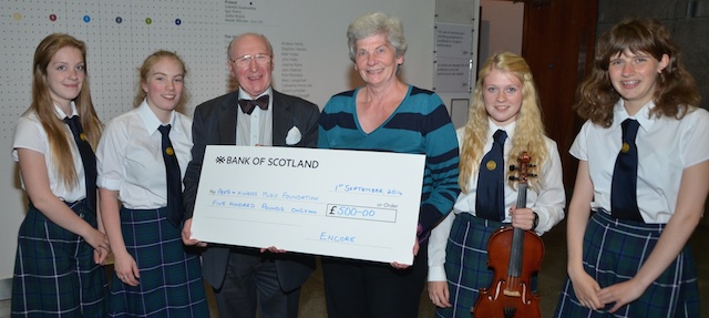 Perth Youth Orchestra members (L–R) Sarah Adam, Katriona Allen,  Sophie Moyes and Louise Brown watch as Henry Neil accepts a cheque for £500 from Encore's Lynda Piper.